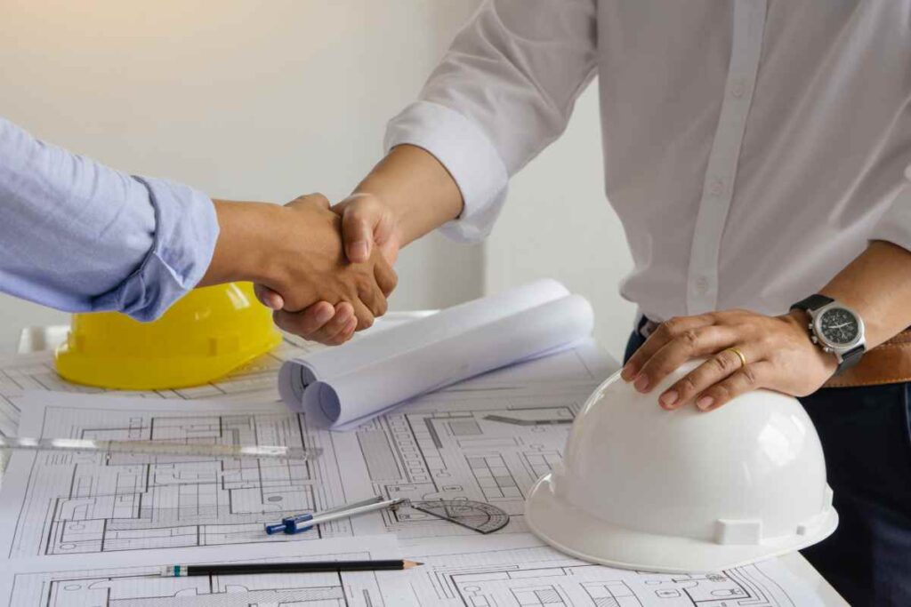 Handshake Over Architectural Plans And Helmets